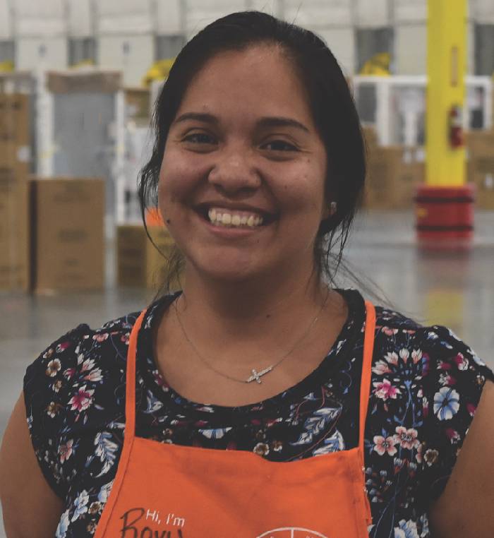 An Area Supervisor smiles into the camera inside a distribution center.