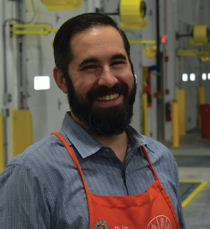 A Market Delivery Operations Manager smiles into the camera in a distribution center.