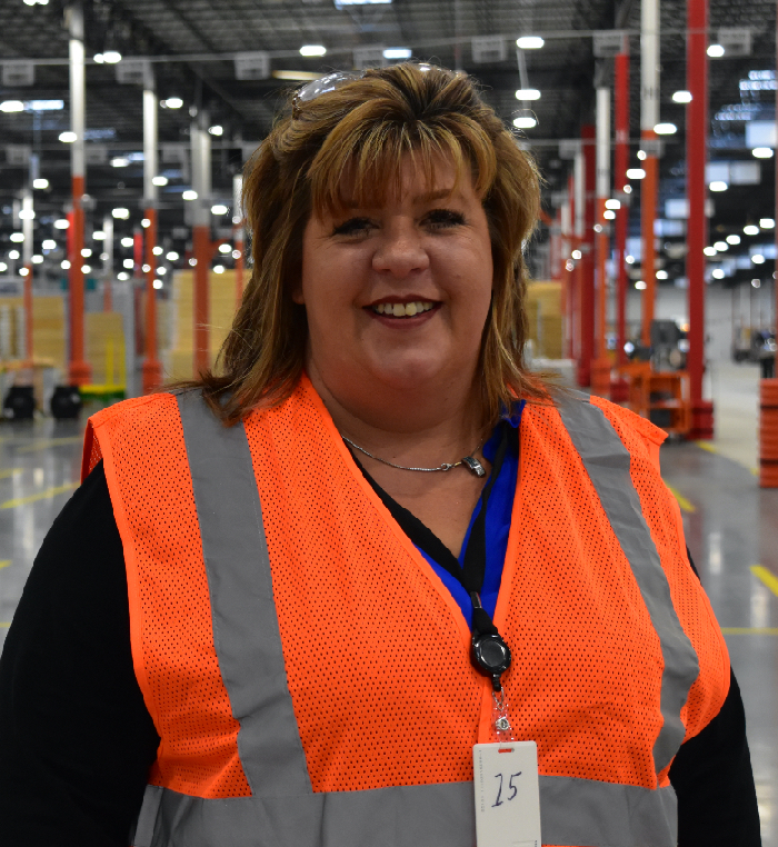 An Operations Manager smiles into the camera in a distribution center.